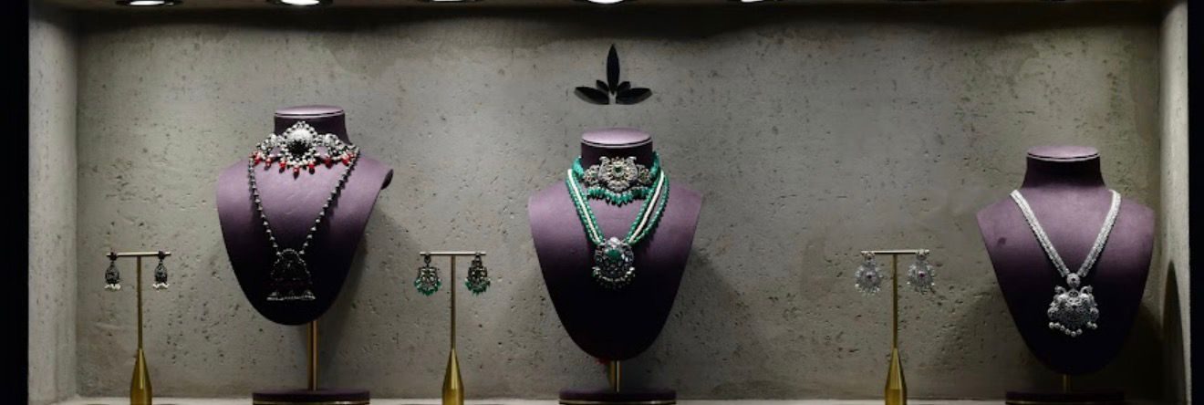 A row of necklaces on velvet busts in a lit wall niche